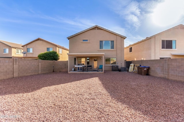 rear view of house featuring stucco siding, a fenced backyard, and a patio area