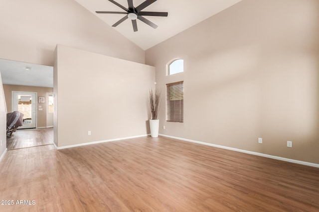 empty room with ceiling fan, baseboards, high vaulted ceiling, and light wood-style flooring