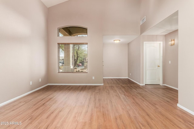 unfurnished room with a high ceiling, wood finished floors, and baseboards