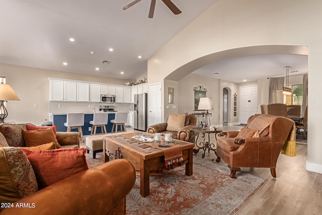 living room with light hardwood / wood-style flooring, high vaulted ceiling, and ceiling fan