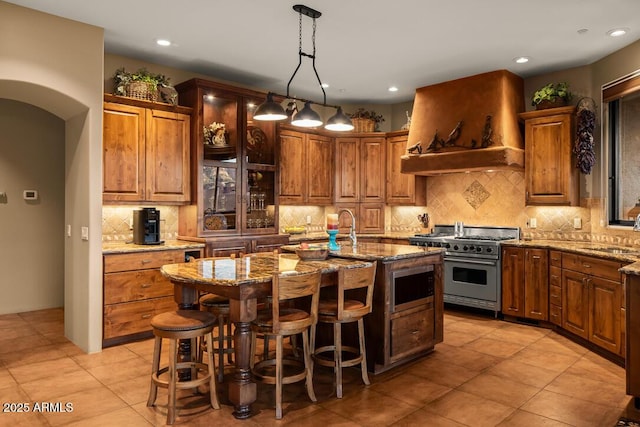 30 Paraiso Corte, Sedona, AZ 86351 - kitchen with stainless steel appliances, custom exhaust hood, light stone countertops, a center island with sink, and backsplash