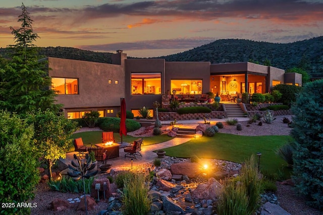30 Paraiso Corte, Sedona, AZ 86351 - back of house at dusk with a fire pit, a mountain view, stairway, and stucco siding
