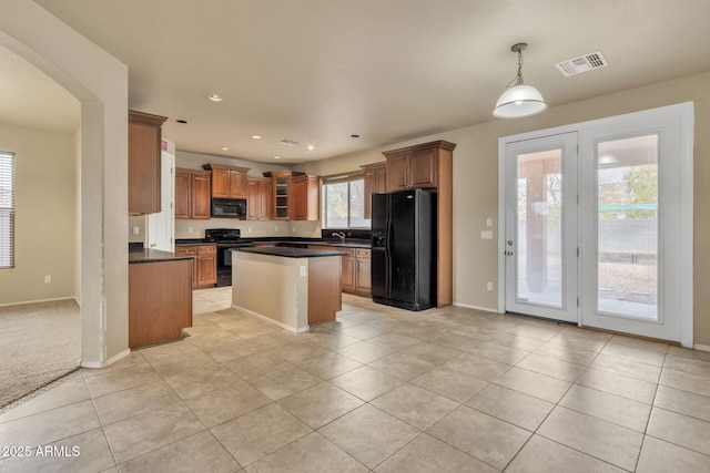 kitchen with black appliances, decorative light fixtures, light tile patterned flooring, and a kitchen island