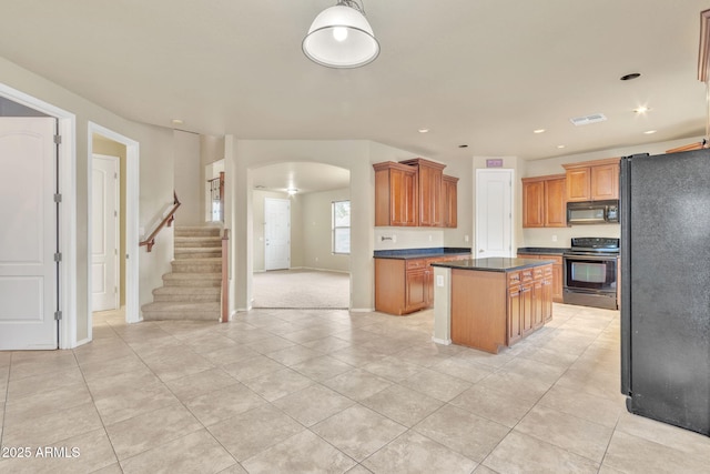 kitchen with light tile patterned floors, a center island, and black appliances