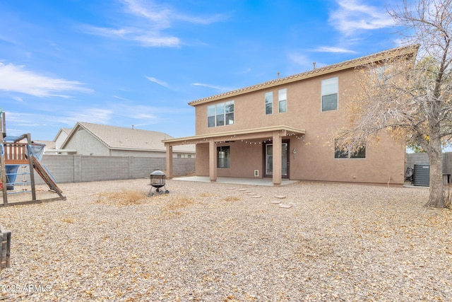 rear view of house with a patio, central air condition unit, a playground, and a fire pit