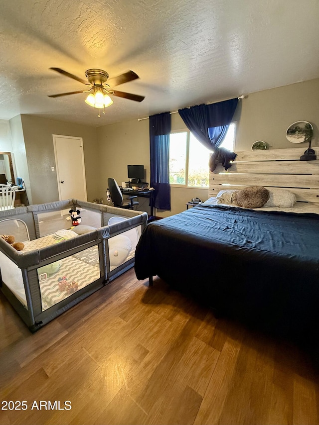 bedroom with ceiling fan, wood-type flooring, and a textured ceiling