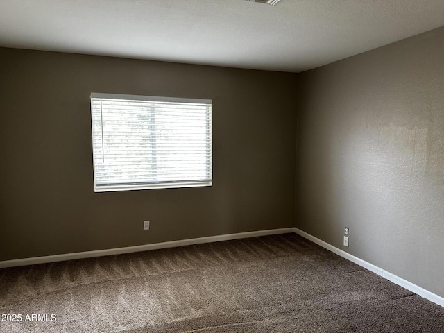 unfurnished room with baseboards and dark carpet