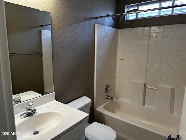 bathroom featuring washtub / shower combination, toilet, vanity, and a textured wall