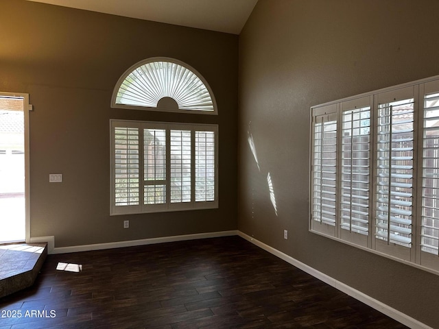 unfurnished living room featuring baseboards and dark wood finished floors