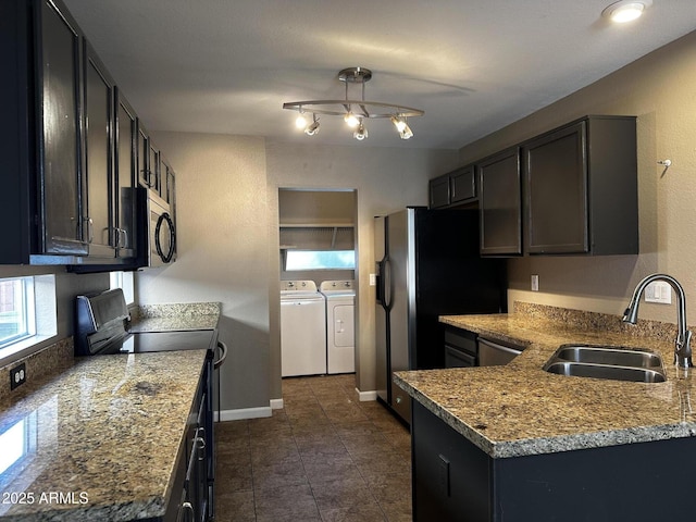 kitchen with a sink, stainless steel appliances, baseboards, light stone countertops, and washing machine and clothes dryer