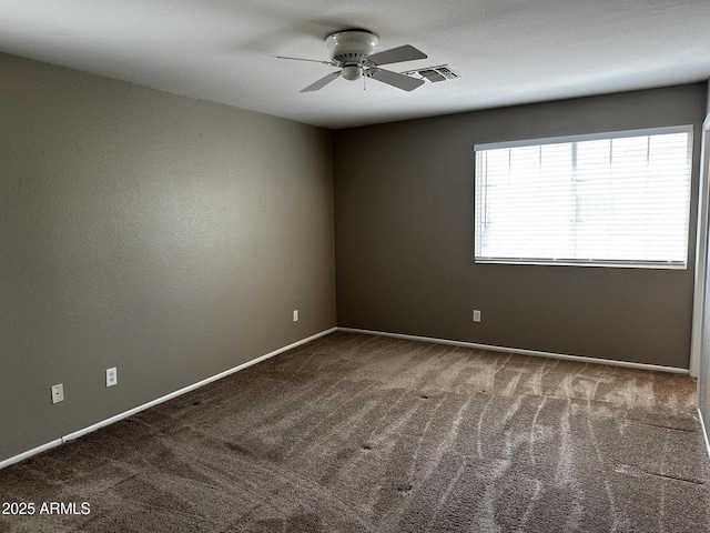 carpeted spare room featuring a ceiling fan, visible vents, and baseboards