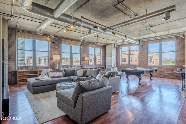 living area with billiards, wood finished floors, a healthy amount of sunlight, and brick wall