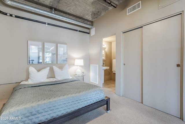 carpeted bedroom featuring ensuite bath, a closet, and visible vents