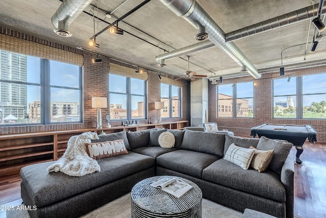 living area with a wealth of natural light, brick wall, and wood finished floors