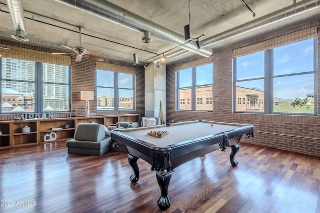 rec room with a healthy amount of sunlight, brick wall, billiards, and wood finished floors