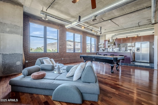 rec room featuring brick wall, rail lighting, dark wood-type flooring, ceiling fan, and billiards