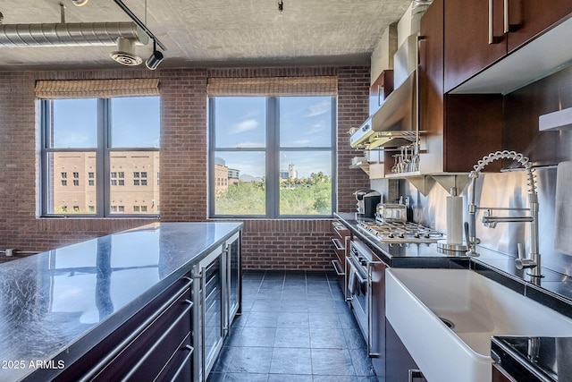 kitchen featuring stainless steel gas cooktop, pendant lighting, dark brown cabinetry, brick wall, and electric stove