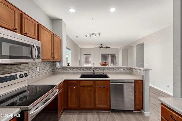 kitchen featuring tasteful backsplash, ceiling fan, sink, light wood-type flooring, and stainless steel appliances