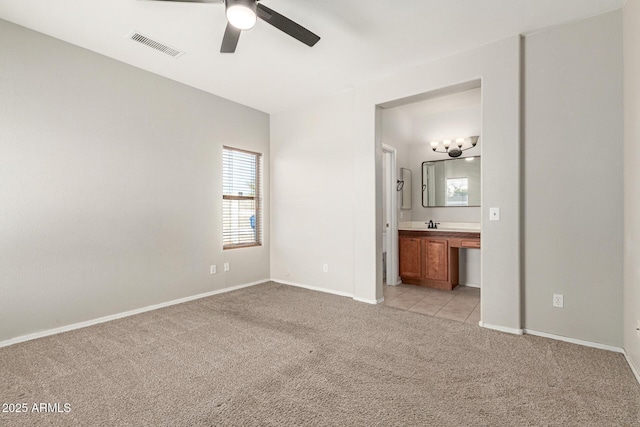 unfurnished bedroom featuring ceiling fan, light colored carpet, ensuite bathroom, and sink