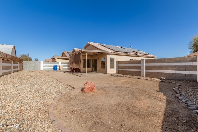 back of property with a patio area and solar panels