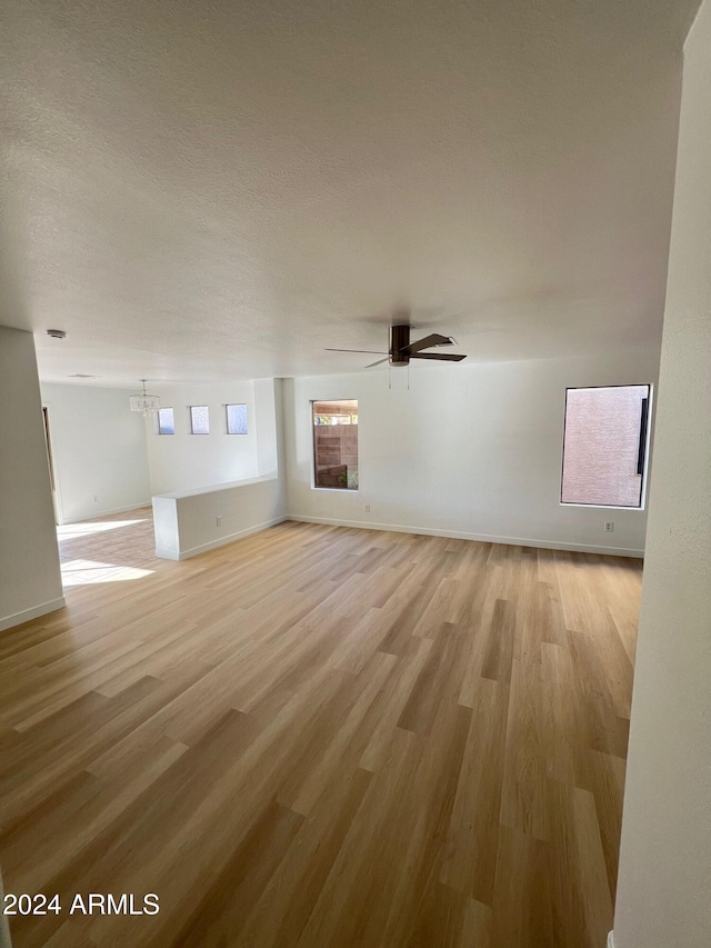 unfurnished living room featuring a textured ceiling, light wood-type flooring, and ceiling fan