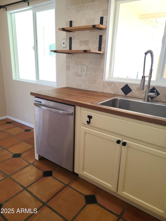 kitchen with stainless steel dishwasher, butcher block counters, plenty of natural light, and sink