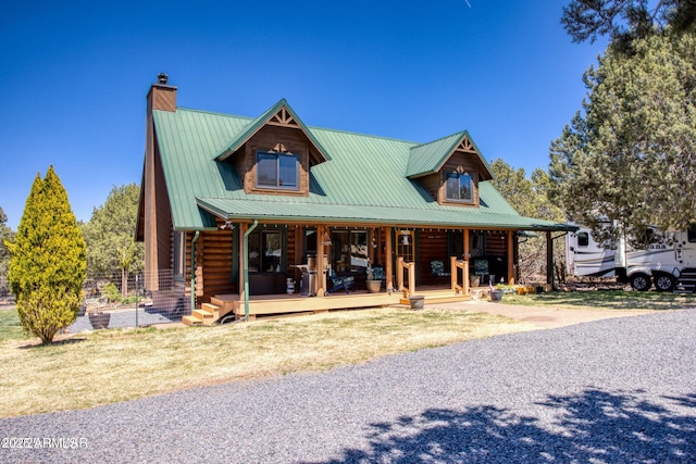 log-style house with a porch, a chimney, log exterior, and metal roof