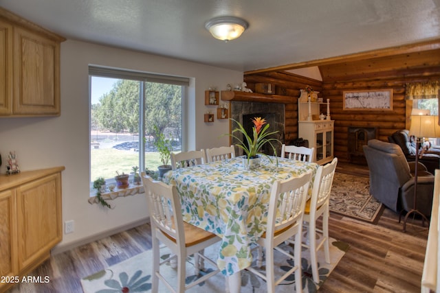 dining area featuring rustic walls, light wood finished floors, and a tile fireplace