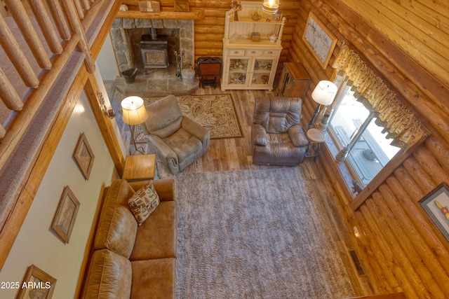 living room with log walls, a wood stove, and wood finished floors