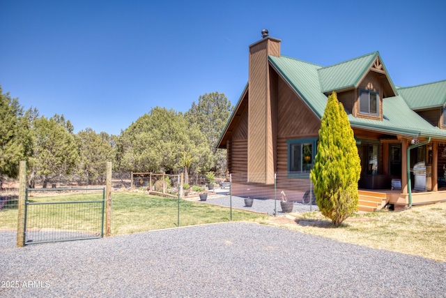 log home with a chimney, metal roof, a porch, a gate, and log exterior