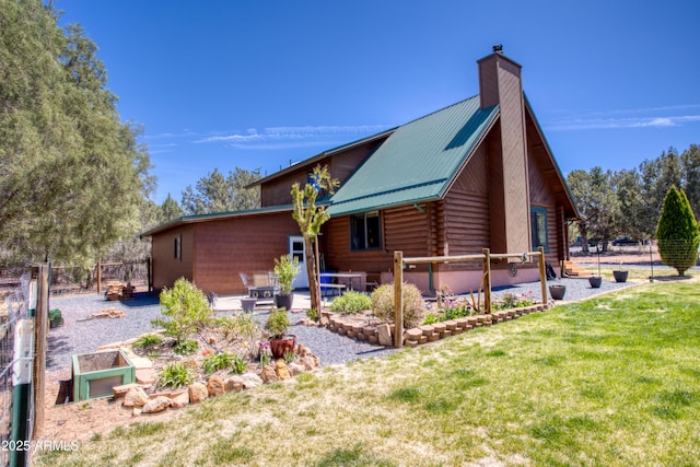 view of side of home with log exterior, a chimney, and metal roof