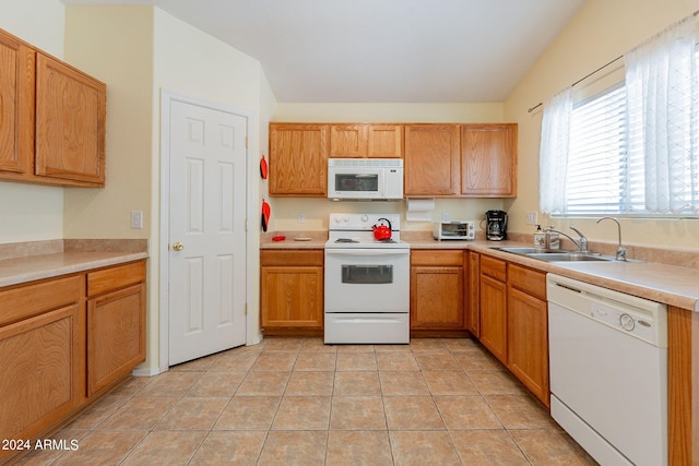 kitchen featuring sink, white appliances, vaulted ceiling, and light tile patterned floors