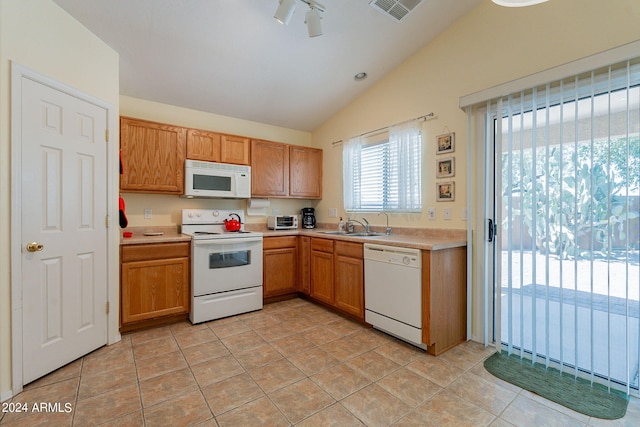 kitchen with sink, white appliances, lofted ceiling, and light tile patterned floors