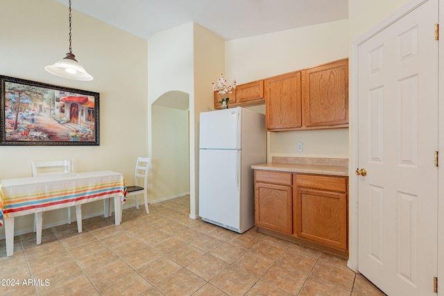 kitchen featuring light tile patterned floors, pendant lighting, white refrigerator, and lofted ceiling