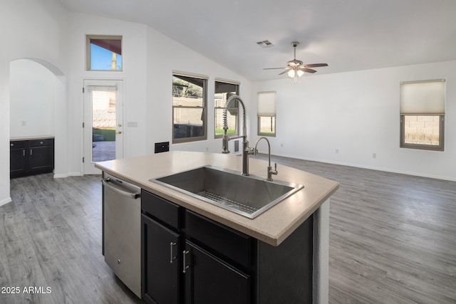 kitchen with a center island with sink, dark hardwood / wood-style flooring, sink, stainless steel dishwasher, and lofted ceiling