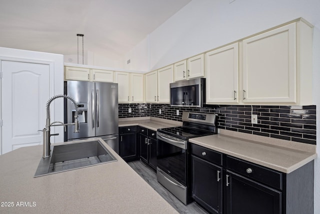 kitchen featuring stainless steel appliances, sink, vaulted ceiling, tasteful backsplash, and pendant lighting