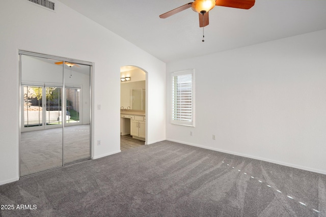 unfurnished bedroom with ceiling fan, vaulted ceiling, ensuite bath, and carpet flooring