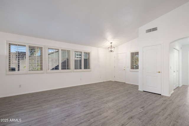 spare room with vaulted ceiling, a chandelier, and hardwood / wood-style floors