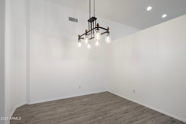 unfurnished dining area with a chandelier and dark hardwood / wood-style flooring