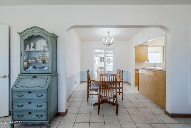 dining area with arched walkways, a wealth of natural light, and light tile patterned flooring