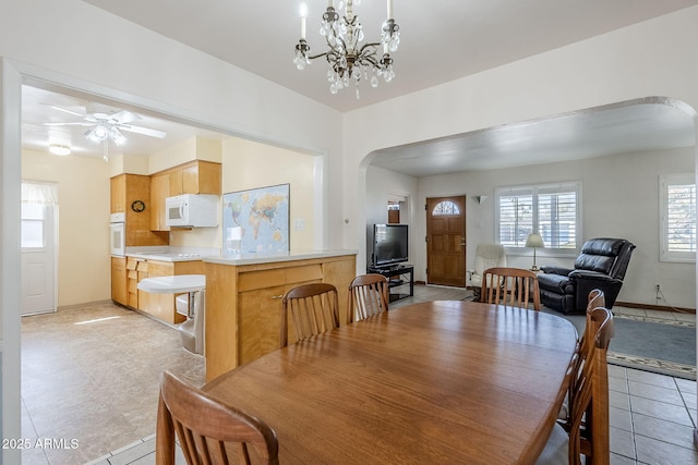 dining room with light tile patterned floors, baseboards, and arched walkways