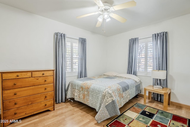 bedroom featuring light wood finished floors, multiple windows, and a ceiling fan