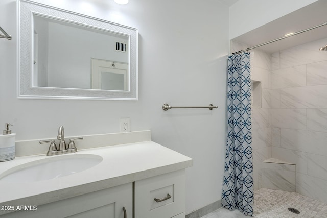 bathroom with visible vents, tiled shower, and vanity