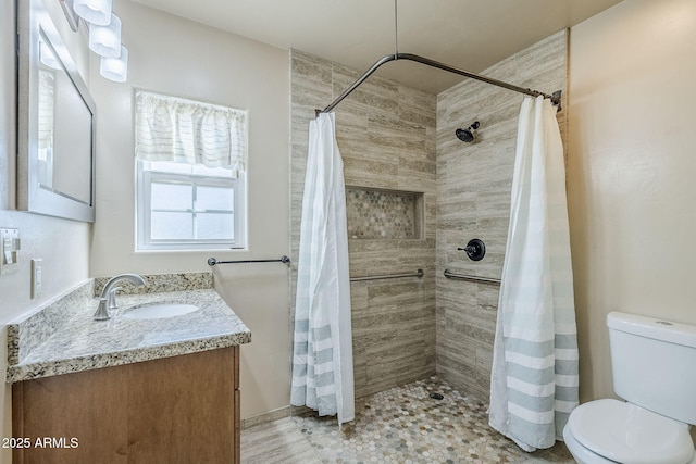 full bath featuring toilet, a tile shower, and vanity