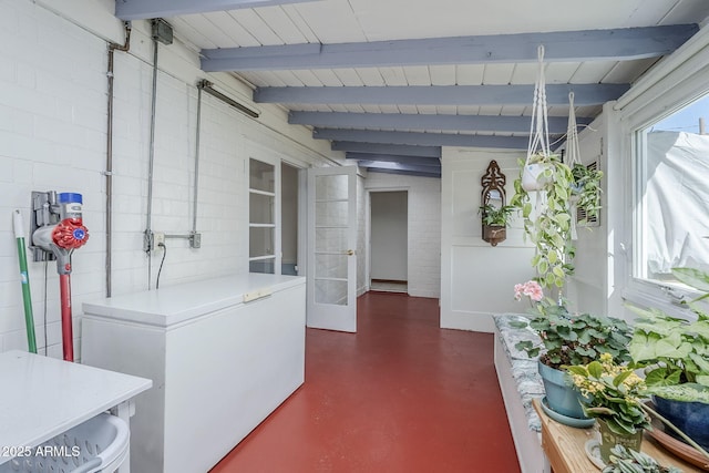 interior space featuring french doors, beamed ceiling, and finished concrete floors