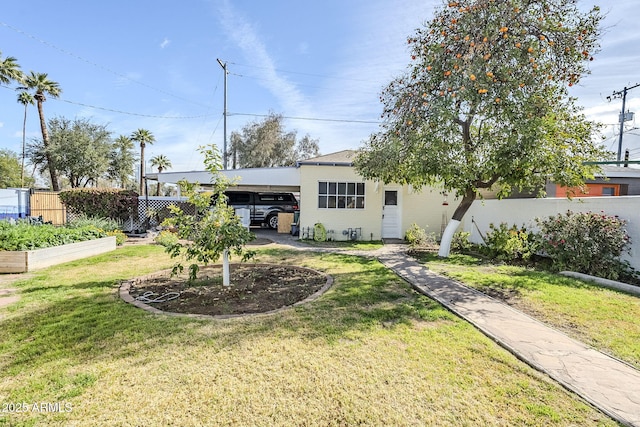 back of house featuring a garden, fence, an attached carport, and a lawn