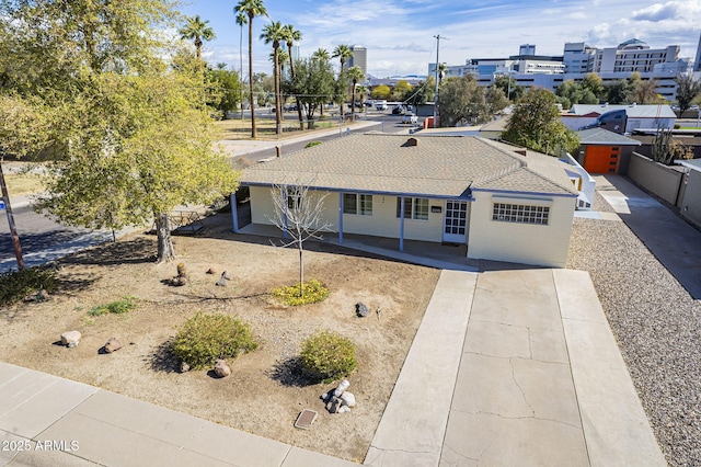 ranch-style house featuring a shingled roof, concrete driveway, and fence