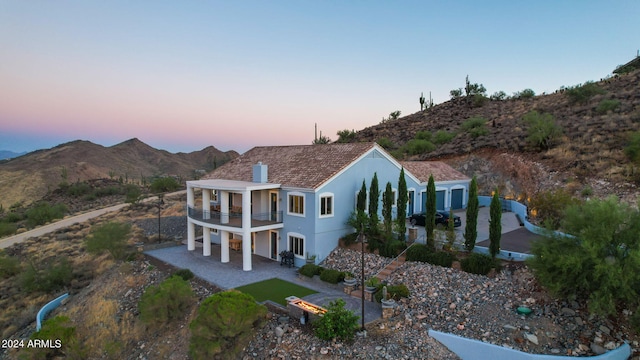 property exterior at dusk featuring a mountain view and a balcony