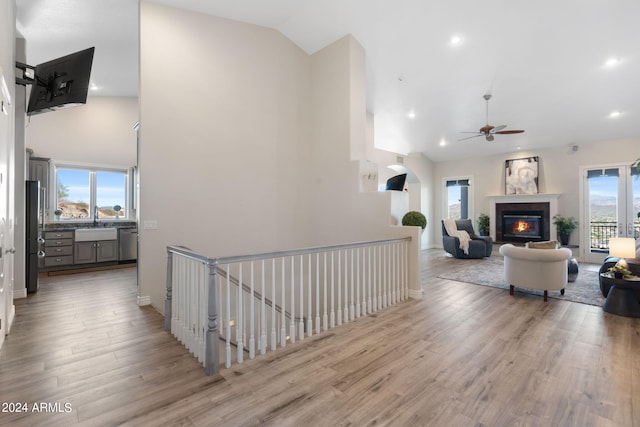 hall with light hardwood / wood-style flooring, lofted ceiling, and sink