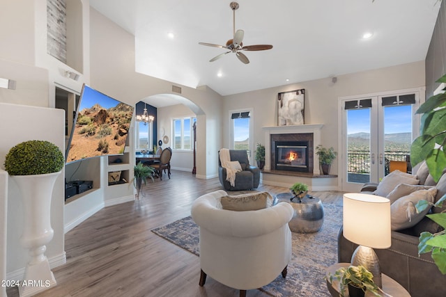 living room featuring a healthy amount of sunlight, lofted ceiling, ceiling fan with notable chandelier, and hardwood / wood-style floors